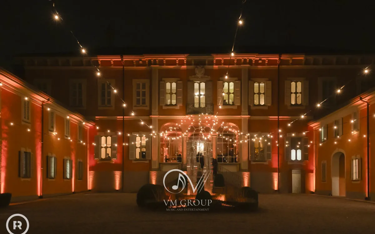 Cortile di Villa Subaglio illuminato con luci a festone e facciata della villa di sera