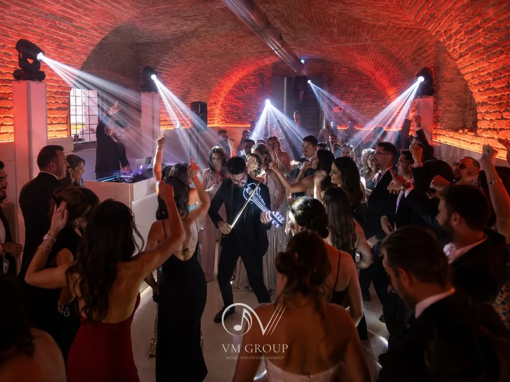 Party nelle cantine di Villa Buttafava: violinista con violino LED tra gli ospiti che ballano, DJ e luci beam sulle volte in mattone